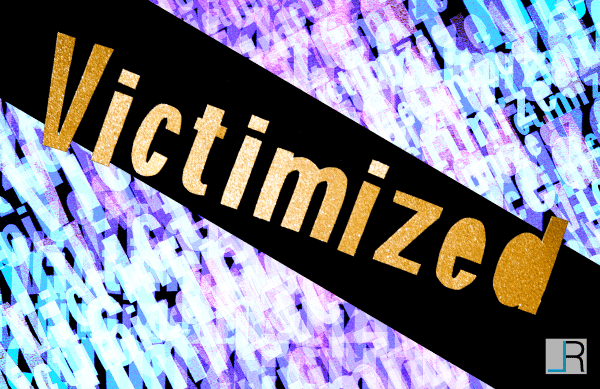 The word Victimized made out of golden paper on a purple blue background